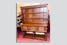 A good quality oak early 20th Century three drawer dresser having a carved frieze, shaped sides