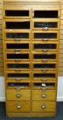 A late twentieth century light wood retailer's haberdashery cabinet with two columns of eight glazed