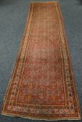 An early twentieth century intricately patterned, mainly rust coloured wool-pile runner-carpet