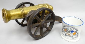 A brassed miniature cannon on a heavy iron work carriage, both 13 ins long (33 cms); together with a