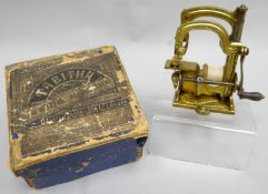 A miniature brass sewing machine 'The Tabitha' by Daniel Judson & Son Ltd of London, with original