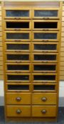 A mid-twentieth century light-oak retailer's haberdashery cabinet with two columns of eight glazed