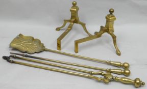 A pair of antique brass fire-dogs together with a three-piece brass fire companion set