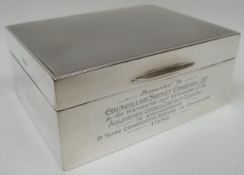 A guilloche decorated silver covered wooden cigarette box with presentation inscription,