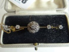 An antique unmarked yellow gold bar brooch with a centre diamond cluster of ten diamonds, flanked by