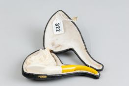 A cased hand carved mauchline pipe with yellow amber stem