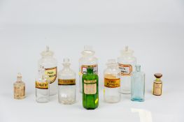 A collection of glass chemist's jars and bottles, ten in all, mostly with labels (stoppers stuck