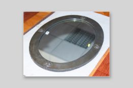 An Art Nouveau oval wall mirror with flat pewter finish and four raised stylized roundels, 22.5 x 30