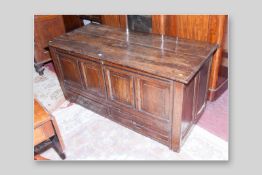 An 18th Century oak mule chest, large four plank top with moulded edge above a four panel front base
