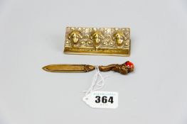 A brass triple section stamp box, the lid having three raised female masks and a small brass