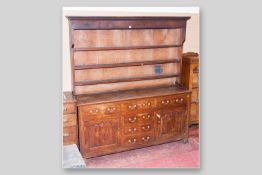 A Georgian oak dresser with closed back three shelf plate rack in pine, the two plank top over an