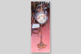A 19th Century rosewood pole screen with floral embroidered face panel (damaged fretwork edging),