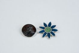 A circular horn cameo brooch in a white metal frame and a white metal and enamel floral brooch