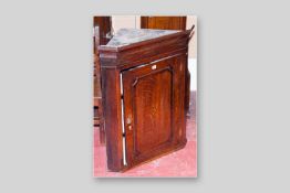 A Georgian oak single door hanging wall cupboard with central Sheraton style inlaid cartouche, brass