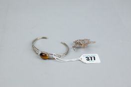 A 925 silver graduated bangle with oval tiger's eye and a white metal filigree flower brooch