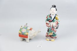A Japanese pottery figure of a gentleman dressed in robes and carrying a gilt decorated fan (some