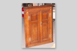 An early 19th Century barrel back oak hanging corner cupboard, a blind frieze above two fielded
