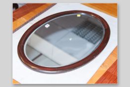 An Edwardian mahogany framed oval bevelled edge mirror, 22 x 32 ins (56 x 81 cms)