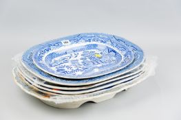 A quantity of blue and white pottery meat platters including a Willow pattern roast platter and an