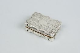 A vinaigrette - a silver vinaigrette with scrolled all over decoration and shaped edging to the lid,