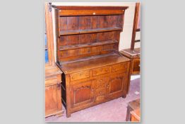 An oak Caernarfonshire dresser having a simple two shelf rack with shaped crown above a two plank