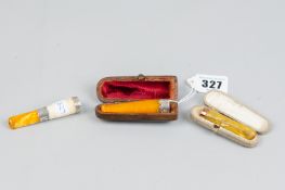 Two cased amber cigarette holders, one silver mounted and the other nine carat gold mounted and a