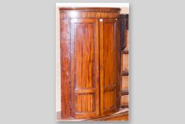 A late Victorian bow fronted two door hanging corner cupboard, the moulded cornice with segmented