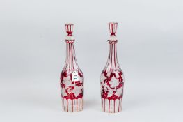 A pair of Bohemian style faceted wine decanters having frosted vine leaf and berry pattern on a ruby