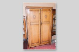 An early 20th Century light oak two door wardrobe, 70.5 x 43 ins (179 x 109 cms)