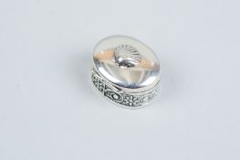 A pill box - an oval 925 silver pill box with scrolled decoration to the body and a hinged lid