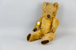 An early 20th Century English straw filled gold plush teddy bear with 'Made In England' tag to his