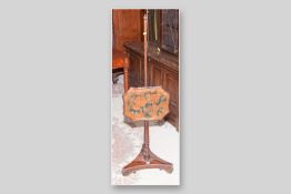 A Victorian mahogany polescreen with shaped adjustable face panel of fruit decorated velvet cloth,