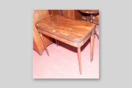 A 19th Century foldover mahogany tea table, the top with reeded edge on turned and tapering