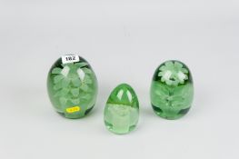 Three graduated Victorian green glass dump weights, all with internal floral decorations, 4.5 x 4