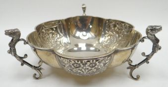 A silver dish, the body composed of six alternating patterned and plain lobes and having three