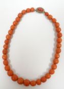 A strand of thirty-six faceted pink coral beads with Sterling silver clasp set with single oval