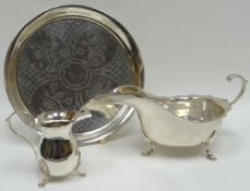 A silver sauce boat of plain form, similar cream jug and a circular silver tray, and a matching