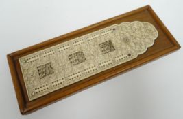 A carved ivory cribbage scorer to a wood mount and incised profusely with floral decoration and
