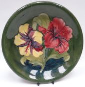 A Walter Moorcroft green-ground tube-lined floral dish, 8.75ins diam (22cms)