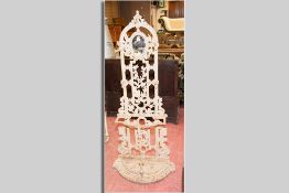 A Victorian cast iron hallstand with small oval mirror, five hat and coat hooks and umbrella and