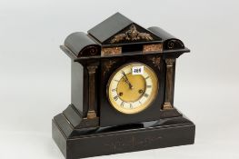 A black slate mantel clock in an architectural style case, the circular dial flanked by Corinthian