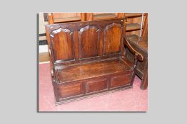 A late 18th/early 19th Century oak settle having three shaped and fielded panels to the back and