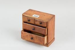 An early twentieth century miniature chest of drawers in mahogany with two short and two long walnut