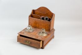 An oak and ebony crossbanded inkstand having a narrow front drawer and with a three section