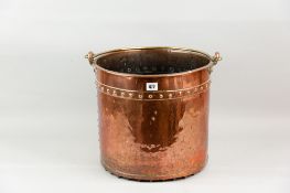 A large circular copper log pan with brass swing handle