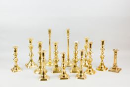 A pair of circular based brass candleholders with slim plain slightly tapered columns, 12.5 ins (