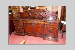 A high Victorian carved four door inverted front sideboard, the raised panel back with excellently