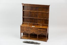 A miniature model of a Georgian oak dresser with plate rack and spice drawers above a five drawer