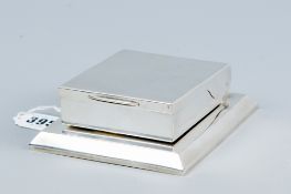 A near square plain silver cigarette box, the rising container having a hinged lid, 10 ozs, London