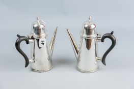 A pair of silver chocolate pots of plain tapered form with domed and knopped hinged lids and